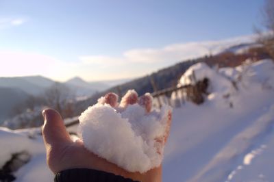 Close-up of hand holding ice cream against sky