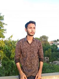 Portrait of young man standing against sky