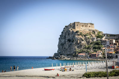 People on beach by sea against clear sky