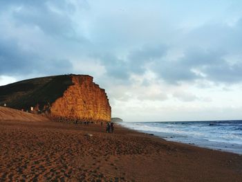 Scenic view of beach against cloudy sky