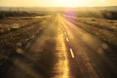 Road amidst illuminated landscape against sky during sunset