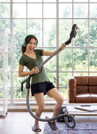 Full length portrait of smiling young woman holding window