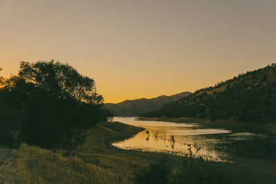 Scenic view of lake against clear sky during sunset