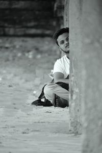 Side view of man sitting on wall