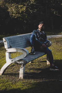 Young man looking away while sitting on land