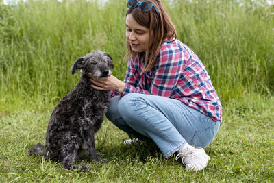 Young woman with dog on grassy field