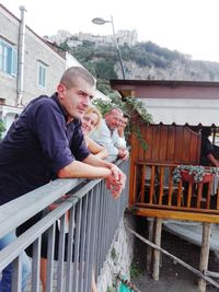 Friends standing by railing against balcony