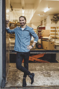 Full length portrait of smiling young businessman standing in new office