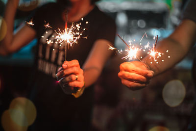 Close-up of people holding sparkler at night