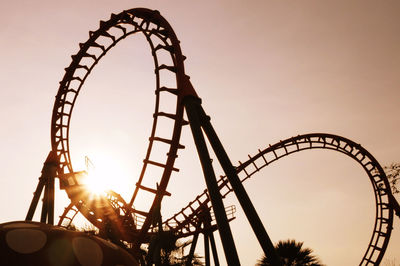 Low angle view of roller coaster tracks against clear sky