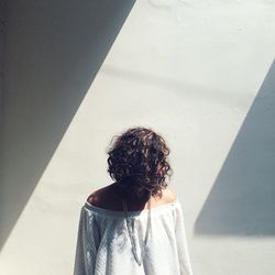 Woman with obscured face standing against wall