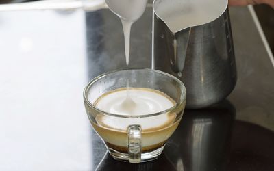 Milk pouring in cup on table