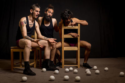 Young jugglers sitting on chairs with balls on stage