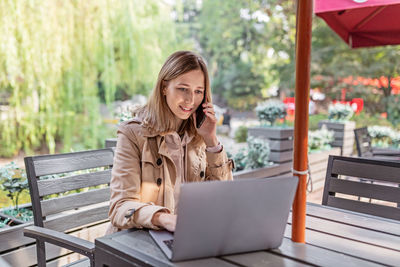 Woman looking at camera while sitting on bench in park