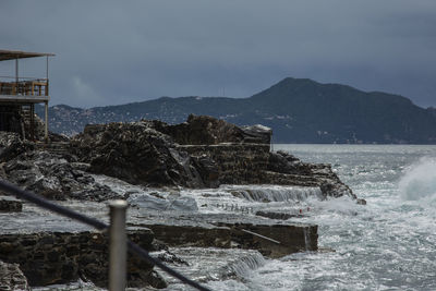 Sea waves splashing on rocks against sky