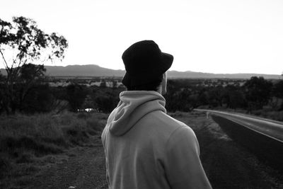 Side view of man wearing hat standing on land against clear sky