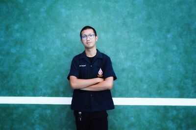 Portrait of young man standing against wall