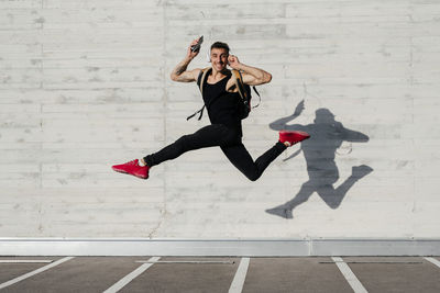 Full length of woman jumping against wall