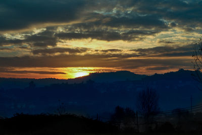 Silhouette of trees against cloudy sky