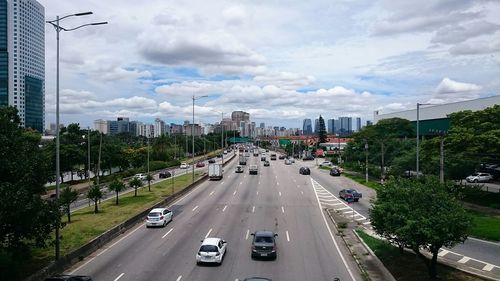 Traffic on road against cloudy sky