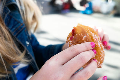 Cropped image of woman holding donut at street market