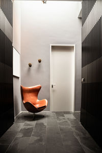 Perspective view of hallway interior with gray striped walls and brown chair placed near entry door
