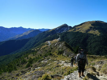 Rear view of man standing on mountain against sky