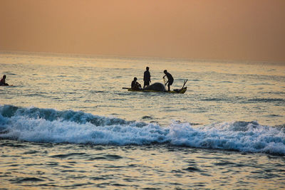 People fishing on sea during sunset