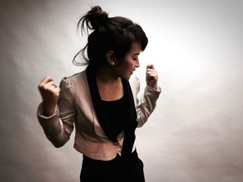 Young woman dancing against wall