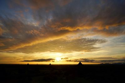 Silhouette landscape against dramatic sky during sunset