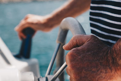 Midsection of man holding motorboat helm on sea