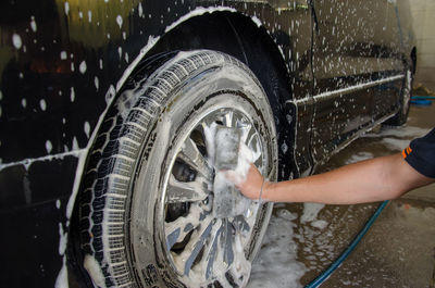 Cropped image of mechanic washing wheel