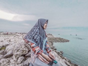 Low angle view of young woman on beach against sky