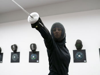 Woman in fencing outfit practicing at gym