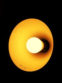 Close-up of illuminated yellow light bulb against black background