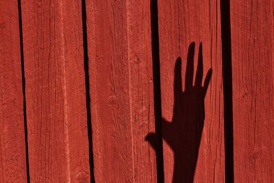 Shadow of human hand on red wood