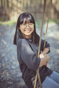 Portrait of a smiling young woman sitting on swing