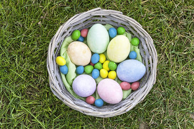 High angle view of colorful easter eggs in basket on field