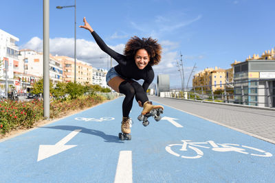Full length of young woman with roller skates on road against sky