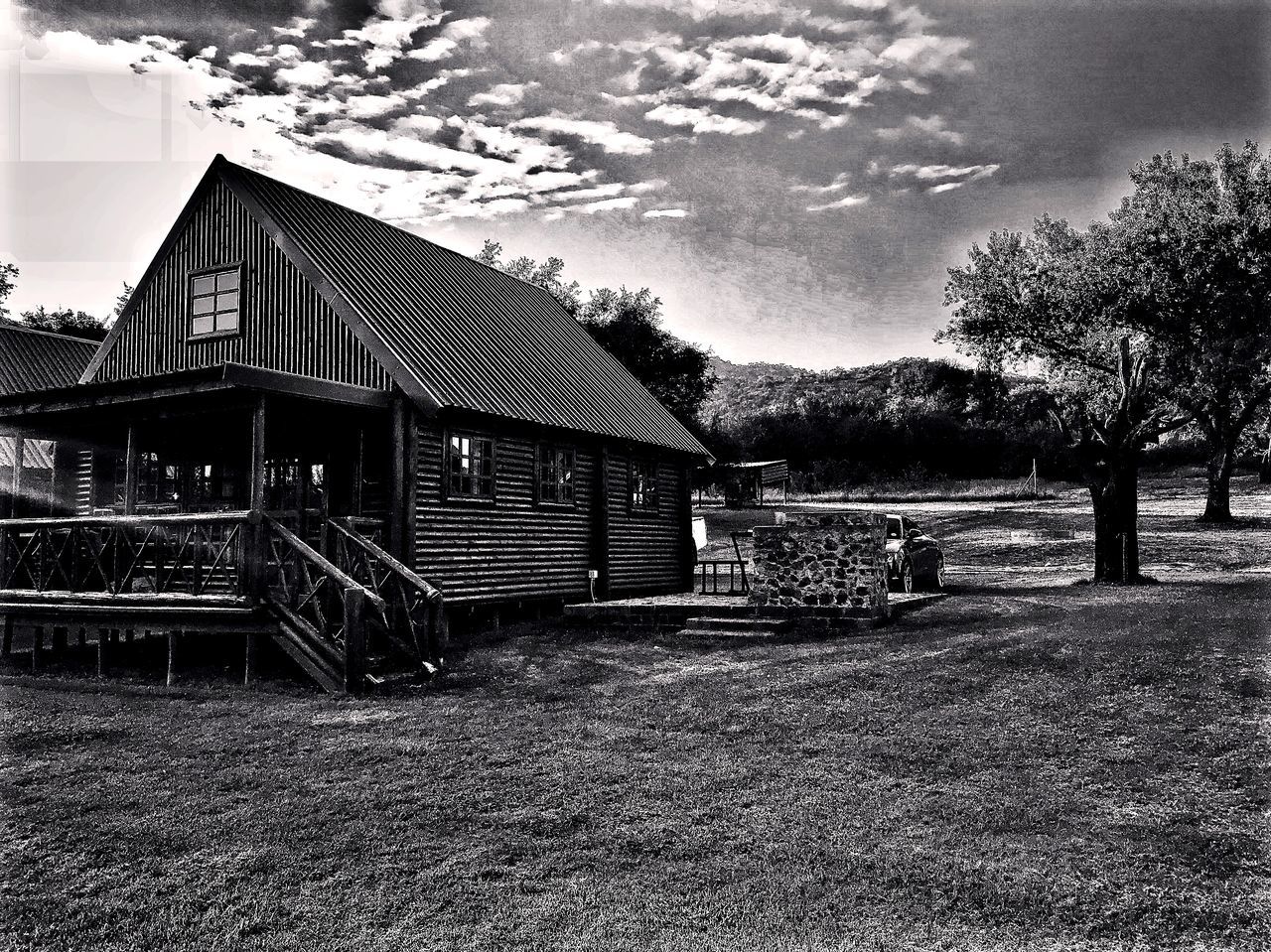 HOUSE ON FIELD BY BUILDINGS AGAINST SKY