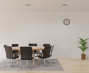 Empty chairs and table against wall