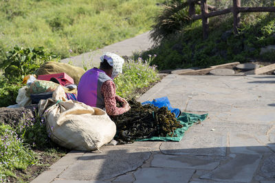 Woman selling sea weed while sitting on footpath