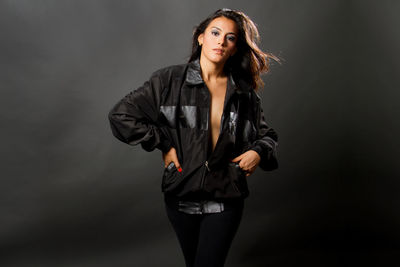 Portrait of beautiful young woman standing against black background