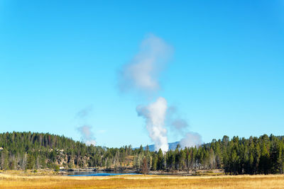 Steam emitting from landscape against sky