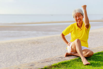 Portrait of smiling young woman sitting on beach