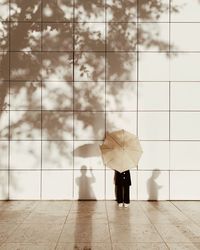 Woman with umbrella standing against building 