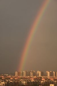 Rainbow over buildings in city against sky