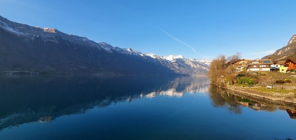 Scenic view of lake and mountains against clear blue sky