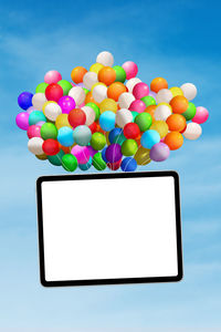 Low angle view of colorful balloons with blank placard against sky