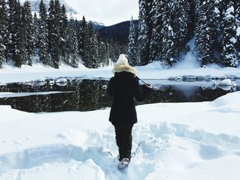 Rear view of woman walking on snow covered land